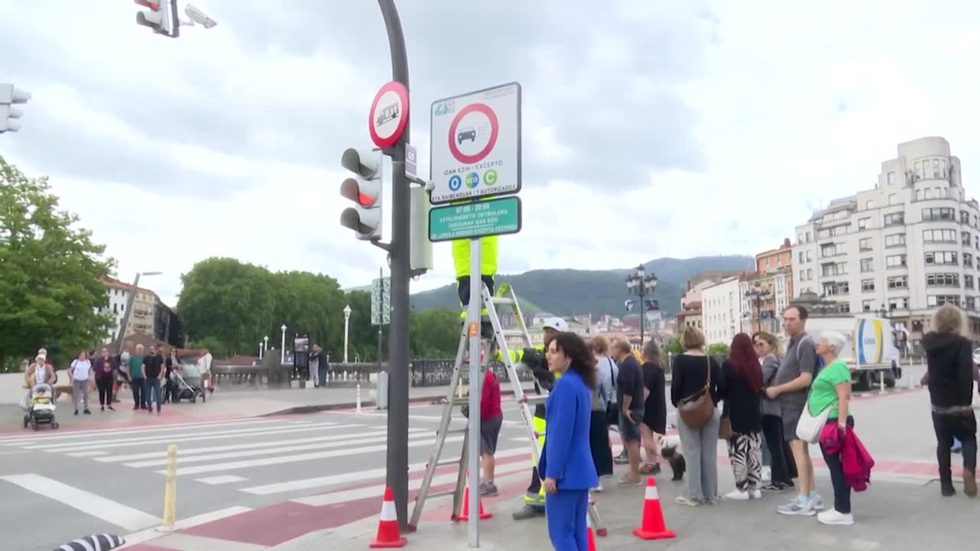 Operarios destapando la señal de acceso a la Zona de Bajas Emisiones implantada en Bilbao