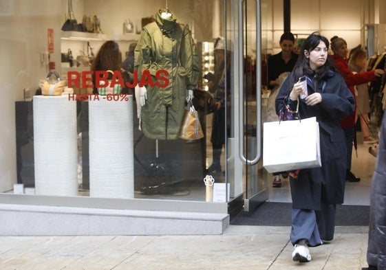 Una joven sale de un comercio de la calle de La Cámara de Avilés con una bolsa.