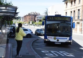 Una mujer espera la llegada de un autobús en Avilés.