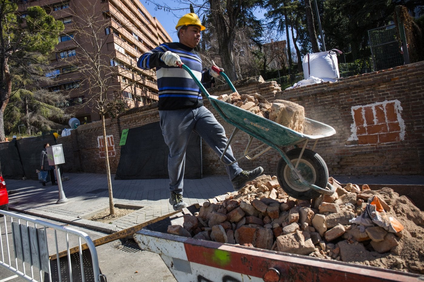 Un operario de una obra tira escombros en un contenedor.