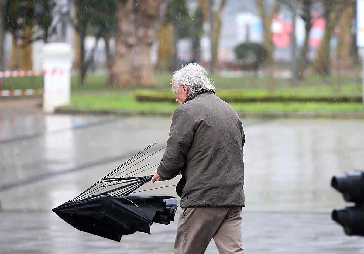 Un hombre, con el paraguas destrozado por el viento durante uno de los últimos temporales en Asturias.