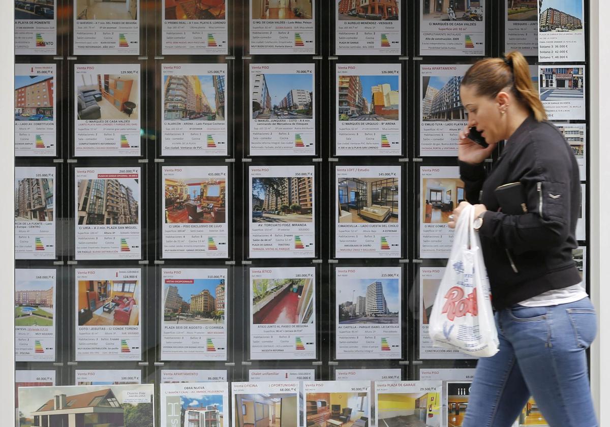 Una mujer pasaa frente a una inmobiliaria.