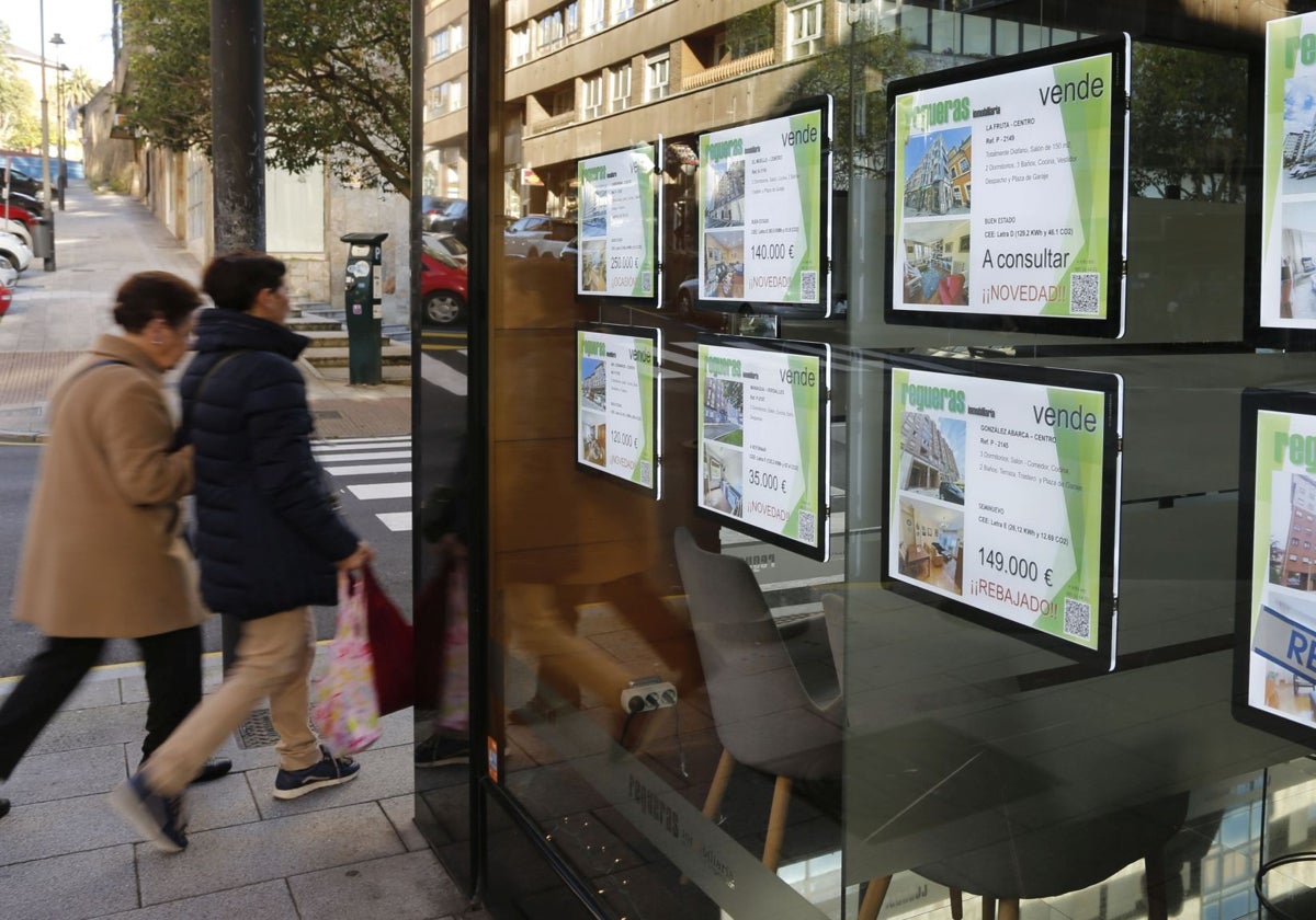 Dos vecinas pasan por delante de una inmobiliaria en Avilés.