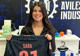 Sara Debén sostiene su camiseta de juego delante del mostrador de la tienda del Real Avilés.
