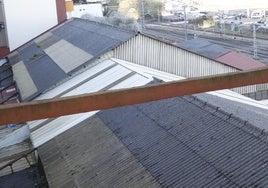Edificaciones con el tejado de amianto situadas frente a las vías del tren.