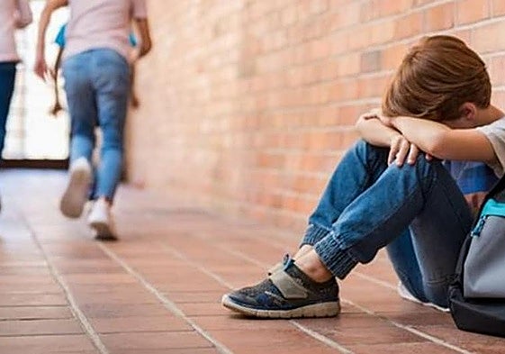 Un niño, solo, en el patio de un colegio.