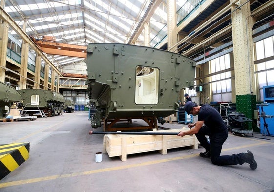 Dos trabajadores realizan trabajos en la fábrica de armas de Trubia.