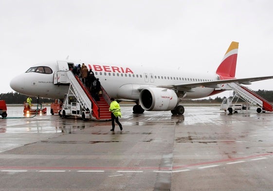 Un grupo de pasajeros suben a un Airbus 320 de Iberia estacionado en el aeropuerto de Asturias