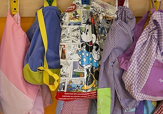 Mochilas de alumnos colgadas en un perchero de clase.