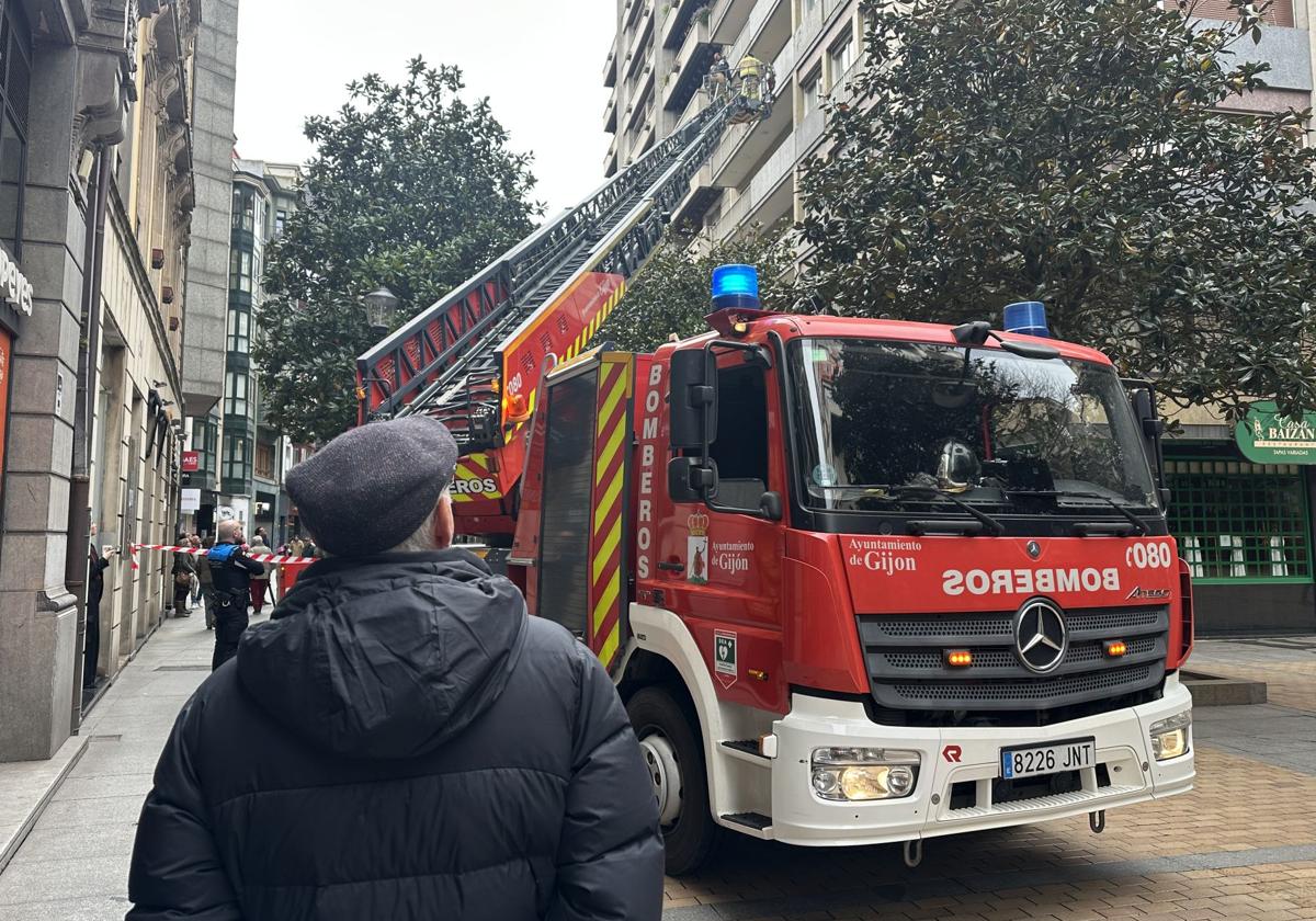 Un hombre observa la intervención de los bomberos en la calle Corrida de Gijón.