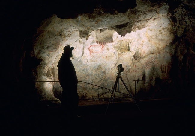 Un arqueólogo, ante una de las pinturas rupestres de la cueva de El Pindal, en Ribadedeva.