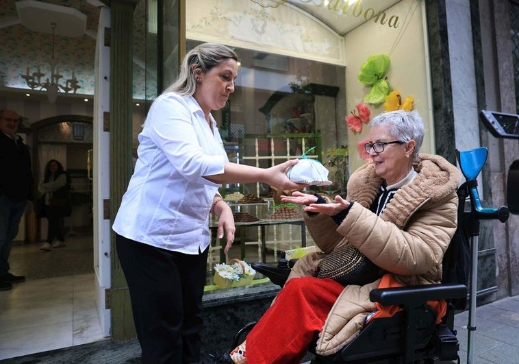 Una de las dependientas de la confitería Balbona, en Gijón, le entrega la 'rosca de San Xurde' a una clienta.