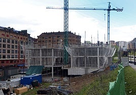 Dos personas pasean por delante de un bloque de viviendas en construcción en la zona de la Ronda Sur.