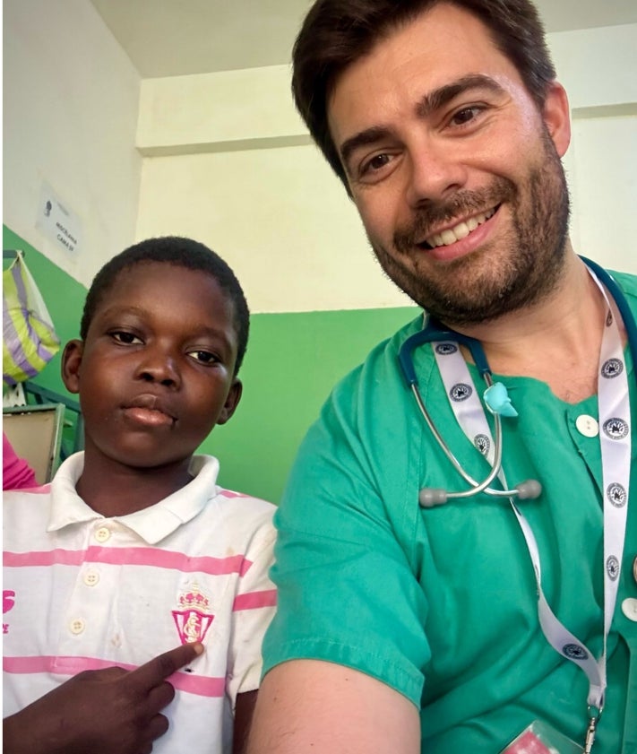 Imagen secundaria 2 - Arriba, los profesionales que participaron en la misión de voluntariado promovida por Sopesur en Guinea-Bisáu, entre ellos Antonio Hedrera (segundo por la derecha) y Álvaro Regueira (agachado). Sobre estas líneas, Pabelinho señala el escudo del Sporting que luce en su pecho. 
