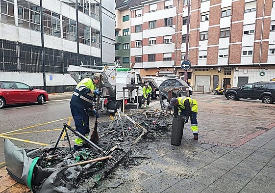 Operarios recogen los restos de los contenedores quemados en la calle la Justicia, La Felguera