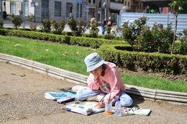 Una de las participantes trabaja en su dibujo sobre el suelo del parque del Muelle.