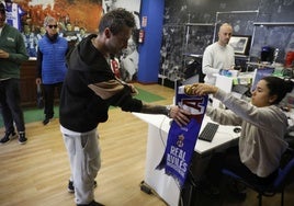 Un aficionado recibe una bufanda de regalo al sacar su entrada en la tienda del club.