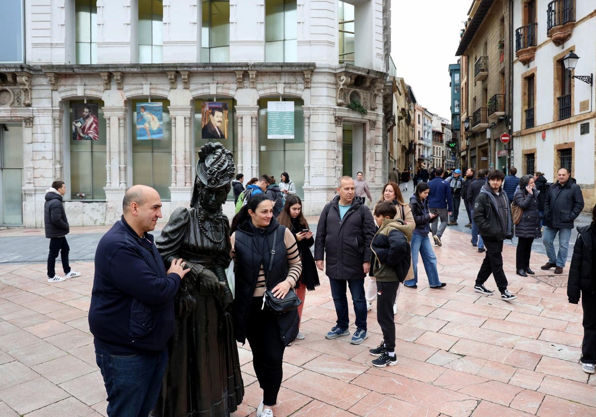 Una pareja de turistas se inmortaliza con la figura de 'La Regenta' en Oviedo.