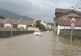 Un vehículo, en plena crecida del río Libardón en Colunga.