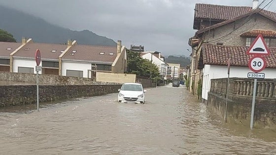 Un vehículo, en plena crecida del río Libardón en Colunga.