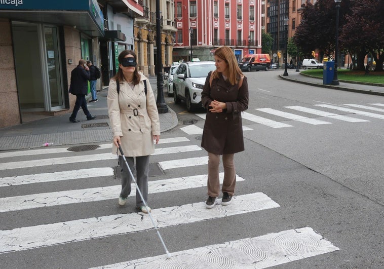 La técnico de rehabilitación de la ONCE Mar Collar da instrucciones para cruzar un paso de peatones no regulado por semáforo en el centro de Gijón.