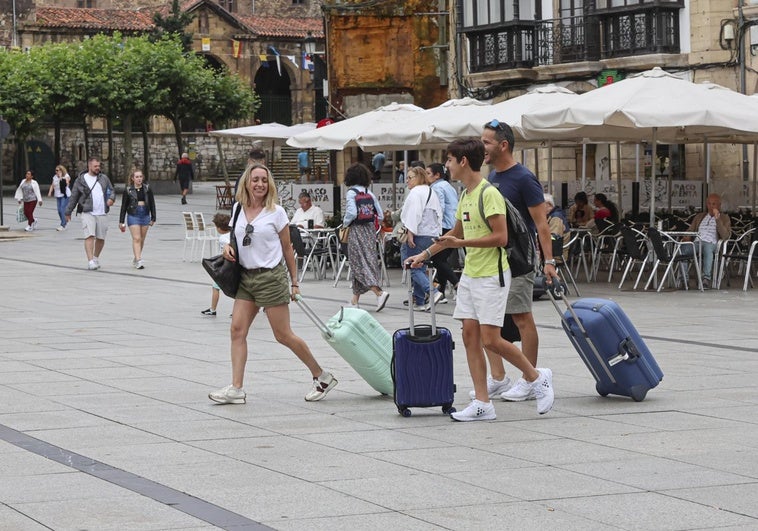 Un grupo de turistas pasea con sus maletas por la avilesina plaza de España.