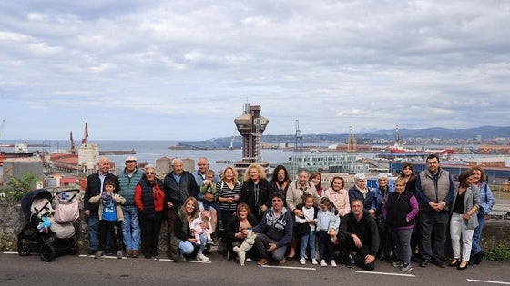 Los vecinos de El Muselín reunidos frente a la sede vecinal del barrio, en el fondo de la foto, el puerto de El Musel.