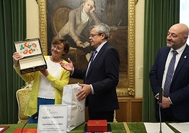 La alcaldesa de Gijón, vestida con los colores de la bandera de Ucrania recibe un presente del embajador del país en España, Serhii Pohoreltsev, en presencia del concejal de Servicios Sociales, Guzmán Pendás.