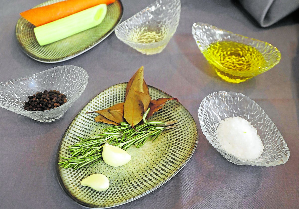 Por arriba y siguiendo las agujas del reloj, vinagre, aceite, sal, laurel, romero, ajo, pimienta, apio y zanahoria, básicos para hacer un escabeche.