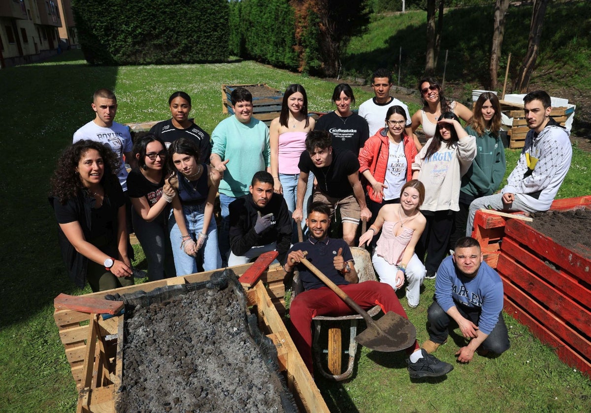 Jóvenes de la asociación Mar de Niebla posan con los huertos elevados que están construyendo en el jardín de los apartamentos del ERA.