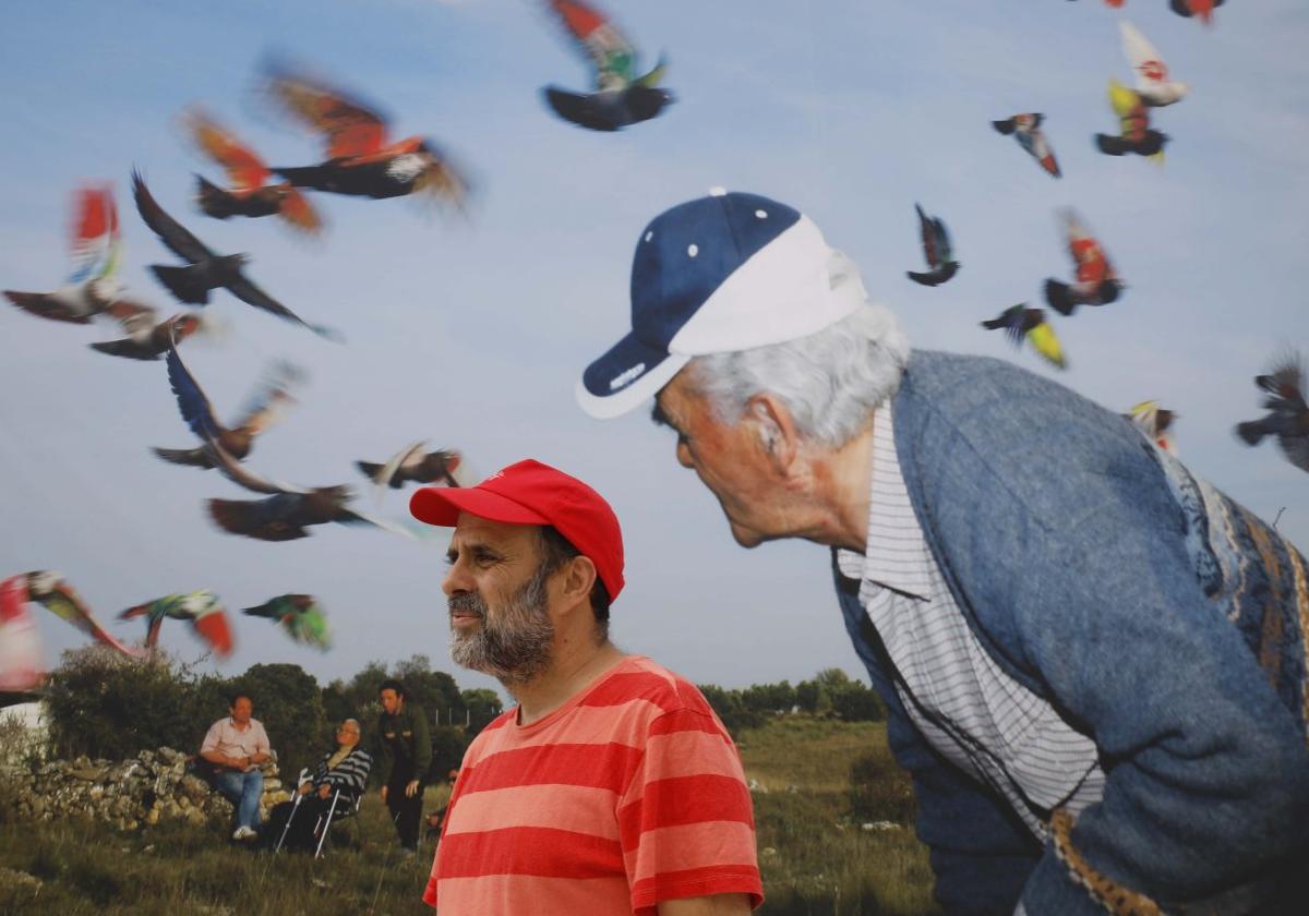 Ricardo Cases, con gorra roja, posa ante una de sus fotografías en la plaza del Centro Niemeyer.