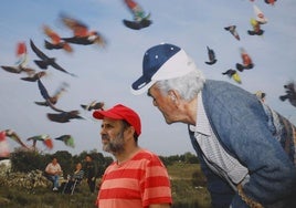 Ricardo Cases, con gorra roja, posa ante una de sus fotografías en la plaza del Centro Niemeyer.