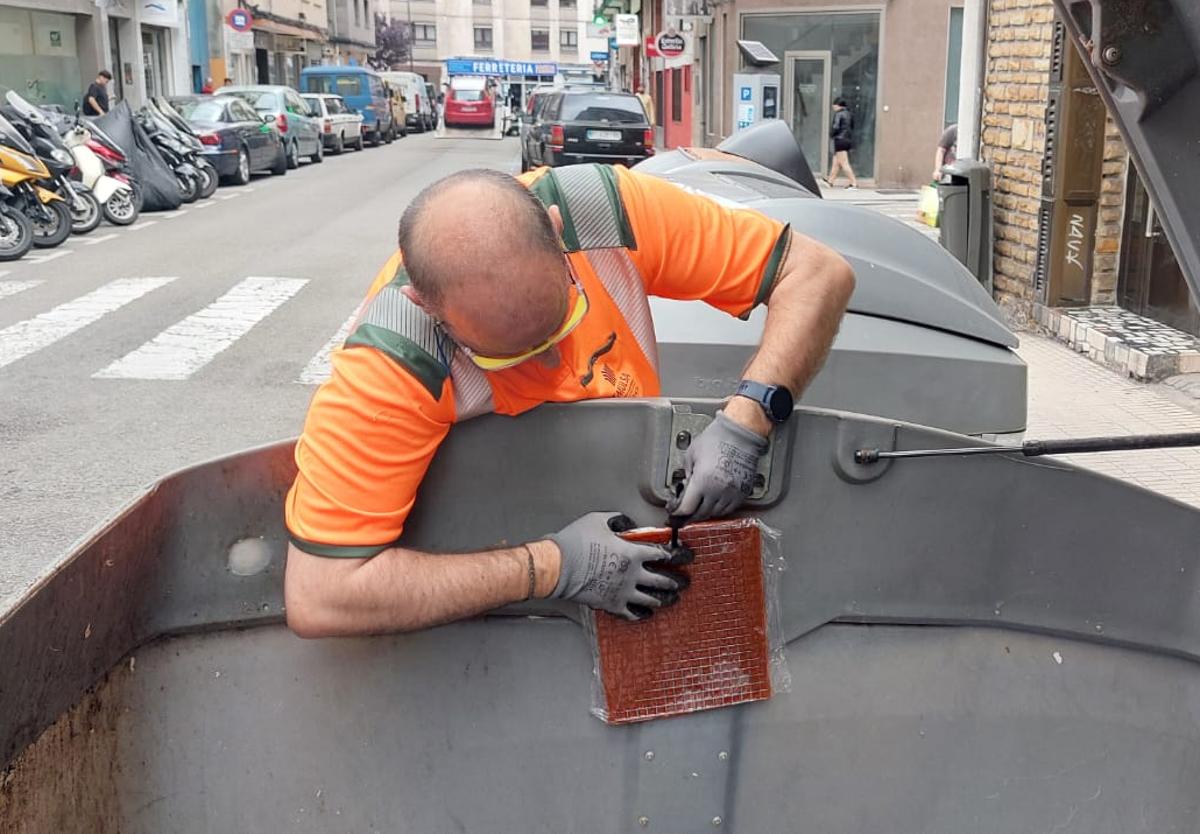 Un operario de Emulsa instalando una placa antiolor en un depósito de residuos orgánicos y resto de la ciudad.