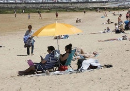 Varios grupos de personas disfrutan de la playa de San Lorenzo, en Gijón