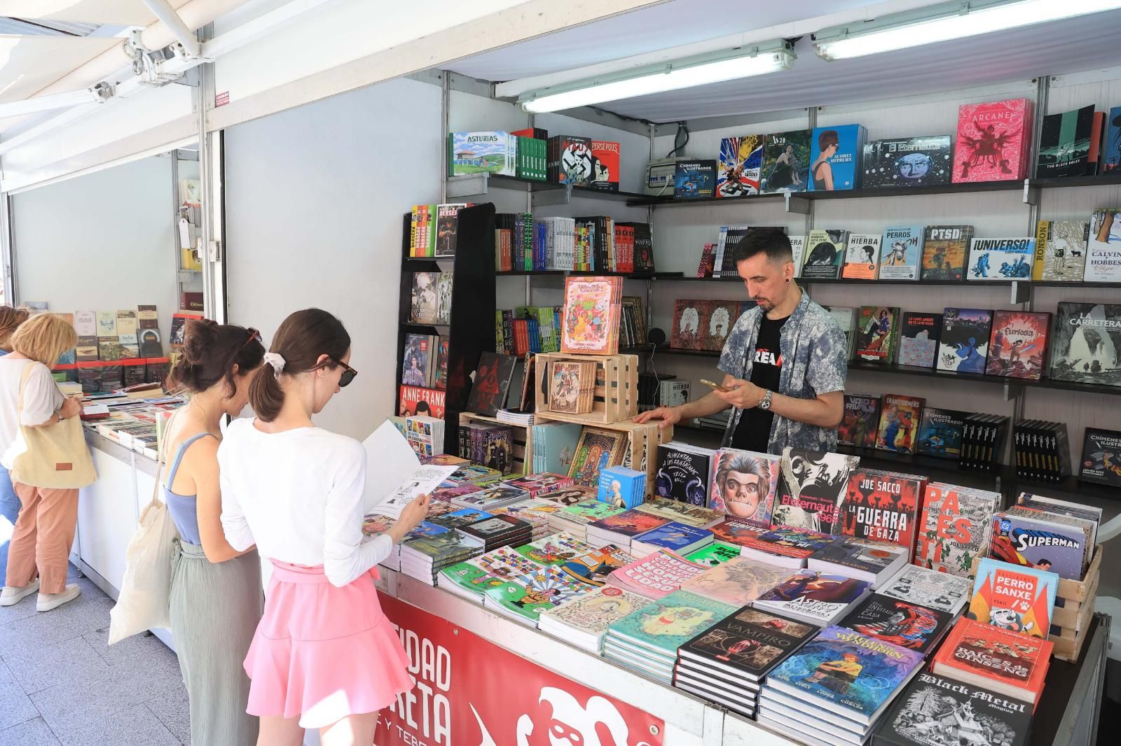 Dos jóvenes ojean algunos de los libros de la feria.