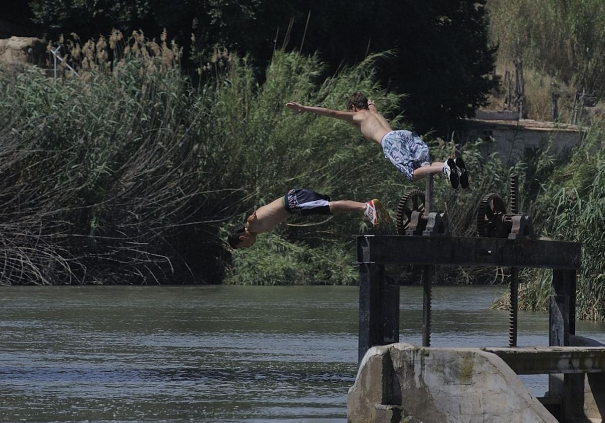 Dos jóvenes disfrutan del verano en un río.