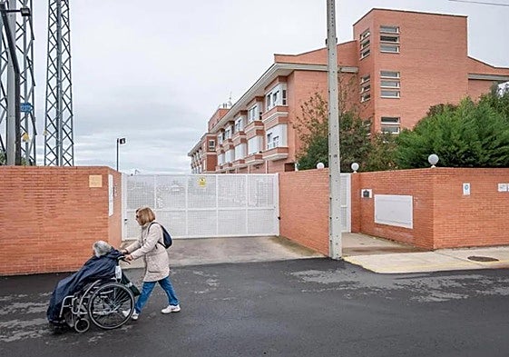 Una mujer pasea a una anciana sentada en su silla de ruedas.