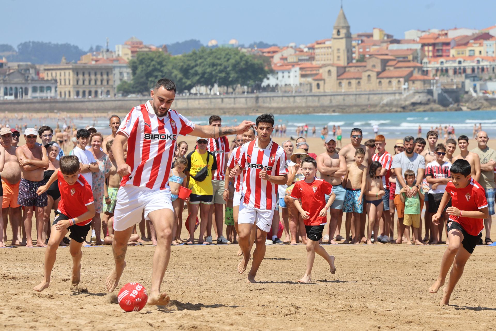 Lucas Perrin y Nacho Martín, con los niños de la Escuela de Fútbol de Mareo, durante el partido en la playa de San Lorenzo.