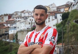 El nuevo fichaje del Sporting, Justin Smith, posa con la primera camiseta de la próxima temporada desde la localidad de Lastres, donde visitó el restaurante 'Native', que regenta una pareja francesa y desde donde el club grabó el vídeo con el que hizo oficial su anuncio .