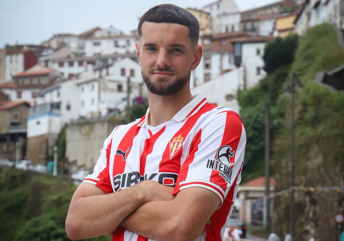 El nuevo fichaje del Sporting, Justin Smith, posa con la primera camiseta de la próxima temporada desde la localidad de Lastres, donde visitó el restaurante 'Native', que regenta una pareja francesa y desde donde el club grabó el vídeo con el que hizo oficial su anuncio .