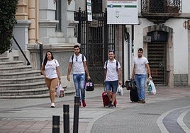 Un grupo de viajeros caminan con sus maletas por Llanes.