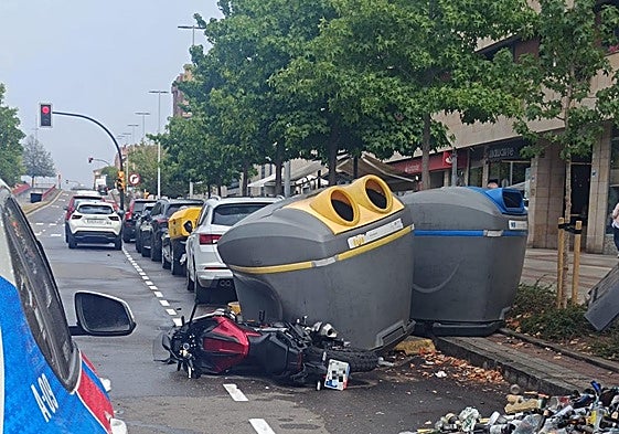 Moto tirada en el suelo en la gijonesa calle Velázquez con los contenedores atrastrados en su caída.