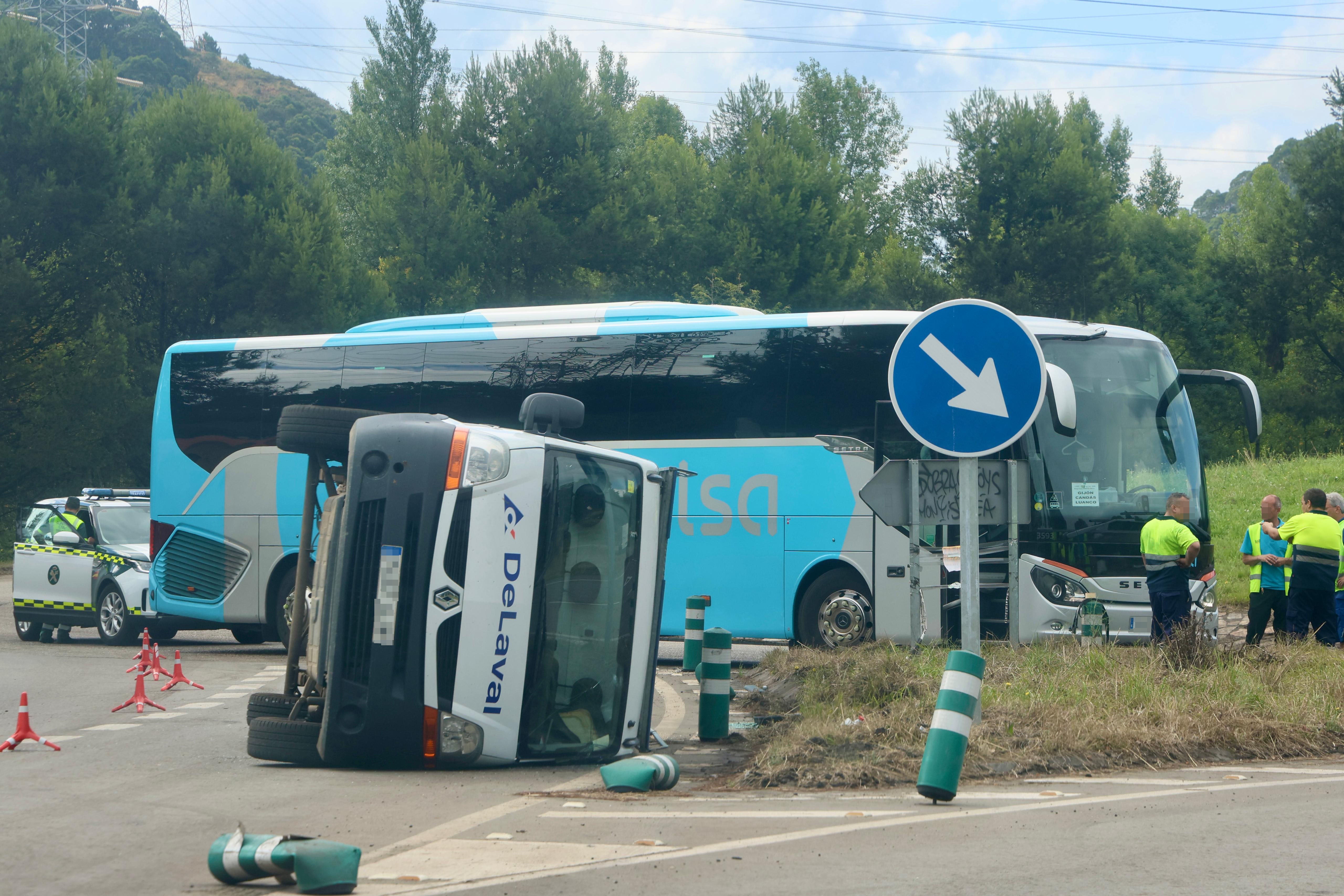  Furgoneta volcada y autobús detenido con el que colisionó en la rotonda de Aboño esta mañana.