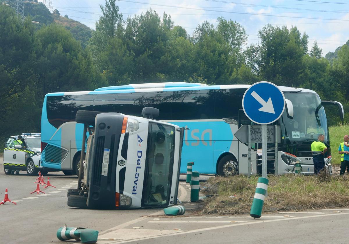 Furgoneta volcada y autobús detenido con el que colisionó en la rotonda de Aboño