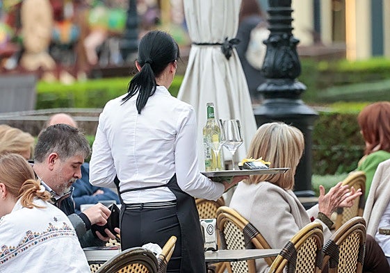 Una camarera atiende a los clientes en una terraza.