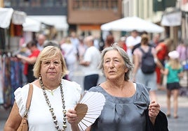 Dos mujeres se abanican, paseando por el casco histórico de Oviedo.