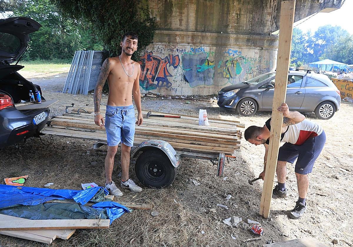 Dos jóvenes retiran tablones de madera y los colocan en su remolque.