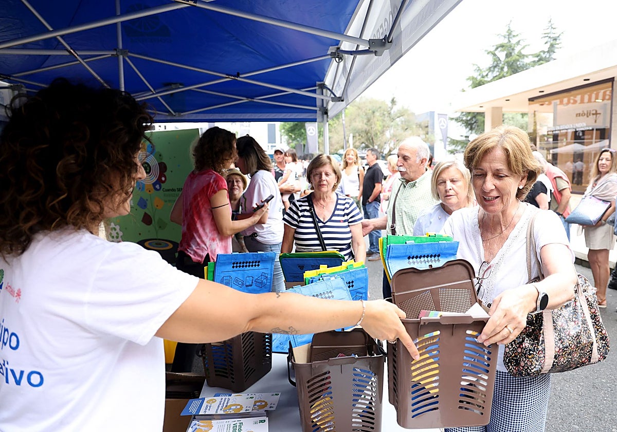 Una voluntaria de Cogersa entrega el cubo marrón y las bolsas separadoras de colores.