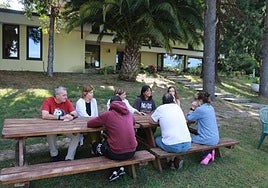 Jesús González, la psicóloga Paula Pérez, la educadora Victoria Canelo y las voluntarias de Cáritas Sherly Roxana Caiza y Lorena Fernández, con varios pacientes en una de las mesas del jardín de La Santina.