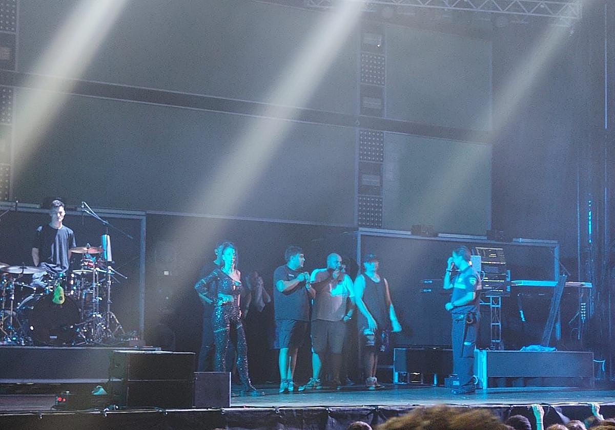 Miembros de la orquesta Tekila, en el escenario, tras detener su actuación en las fiestas de Contrueces de Gijón por un botellazo que golpeó a uno de los cantantes.